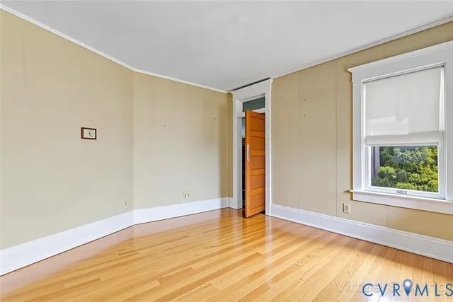 a view of an empty room with wooden floor and a window