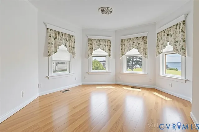 a view of an empty room with a window and wooden floor
