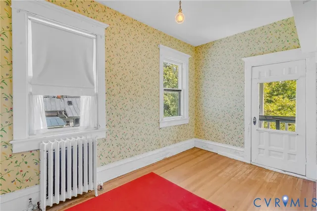 a view of an empty room with a window and wooden floor