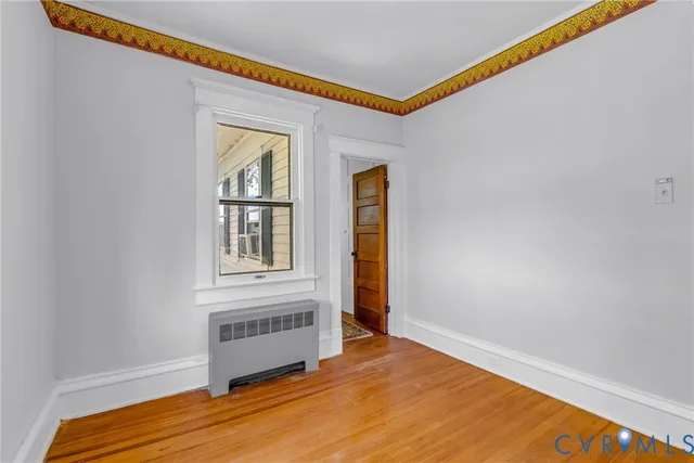 a view of an empty room with wooden floor and a window