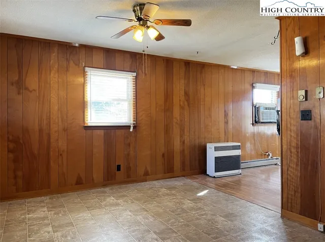 an empty room with chandelier fan and windows