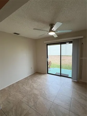 a view of an empty room with wooden floor and fan
