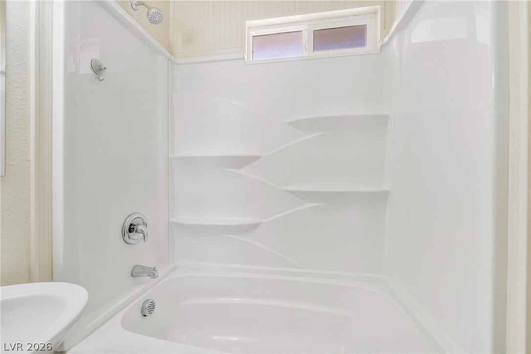 2 California Way Henderson, NV 89015 - Photo 23 of 29 A well-lit, clean white tub and shower combination with convenient built-in shelving.