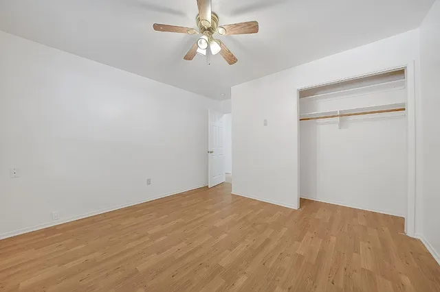 an empty room with wooden floor and ceiling fan