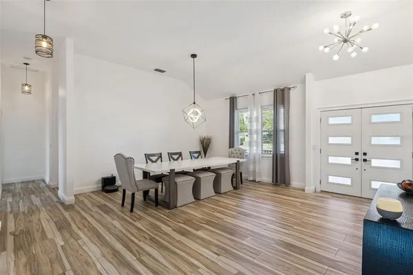 a view of a dining room and livingroom with furniture wooden floor a chandelier