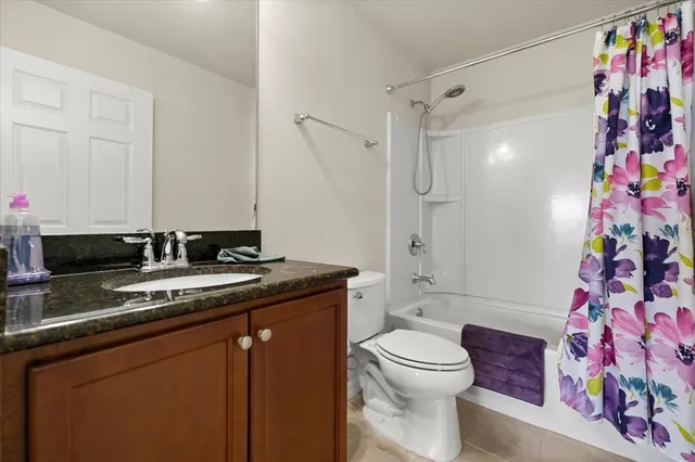 a bathroom with a granite countertop sink a toilet and shower curtain
