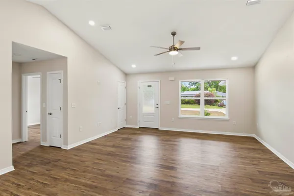 an empty room with wooden floor chandelier and windows
