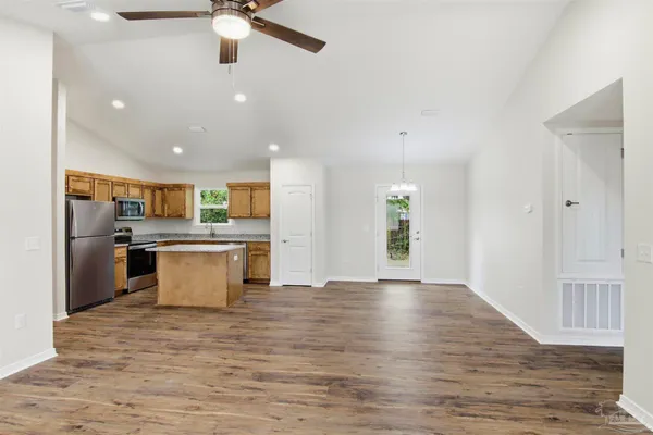 a large kitchen with stainless steel appliances kitchen island a large counter top and wooden floors