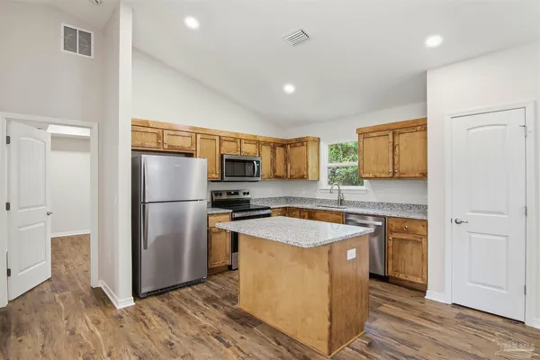 a kitchen with stainless steel appliances granite countertop a refrigerator a sink a stove and oven