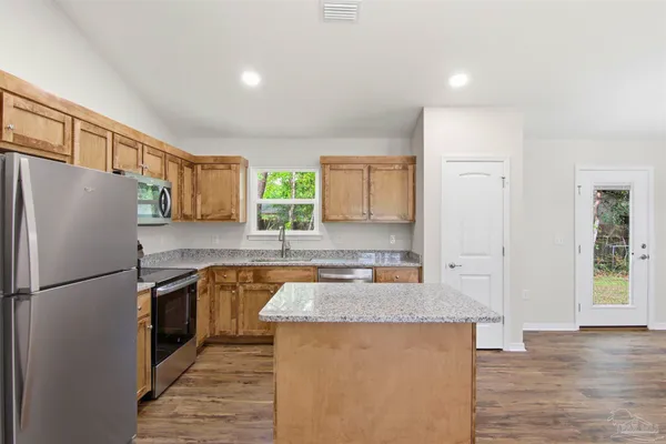 a kitchen with granite countertop a refrigerator stove top oven and sink