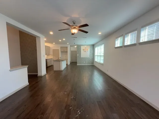 a view of an empty room with window and wooden floor