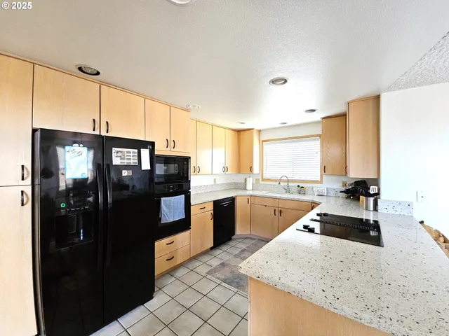 a kitchen with stainless steel appliances granite countertop a refrigerator a stove and a sink with wooden floor