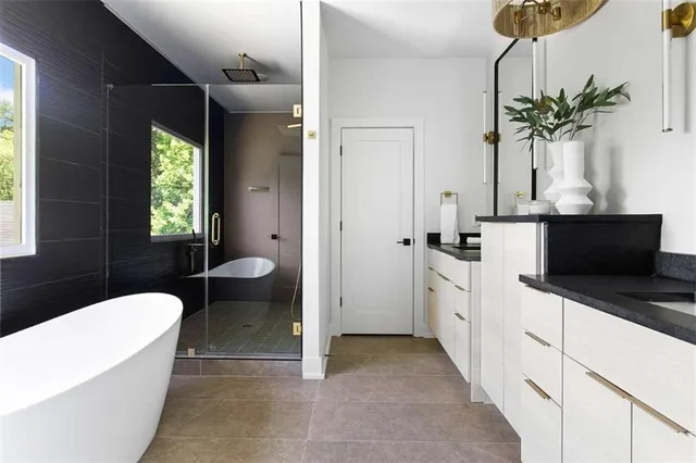 a spacious bathroom with a granite countertop sink a toilet a window and tub