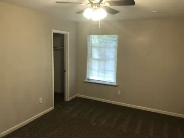 an empty room with windows and fan