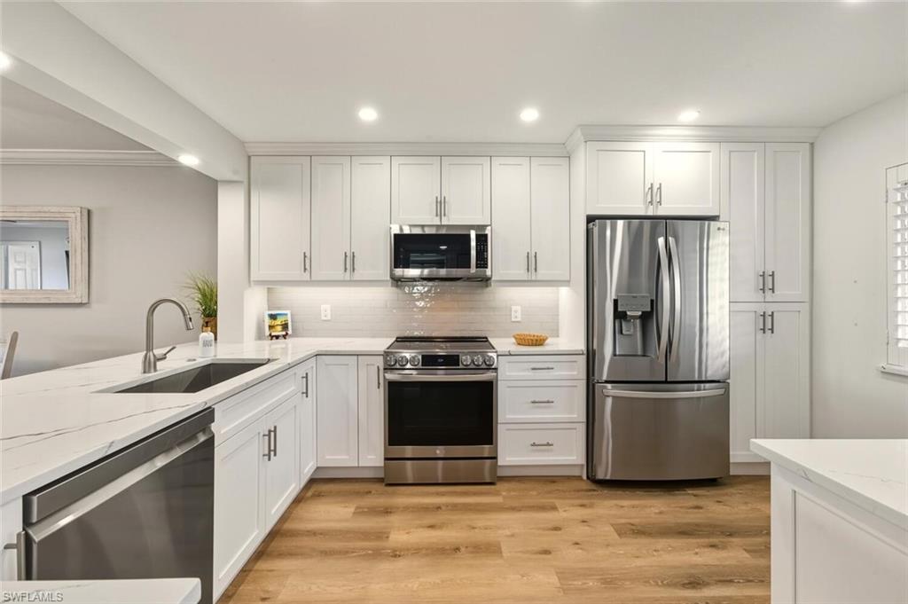 7772 Emerald Circle, Unit 101 Naples, FL 34109 - Photo 5 of 37 a kitchen with stainless steel appliances granite countertop a refrigerator sink and stove
