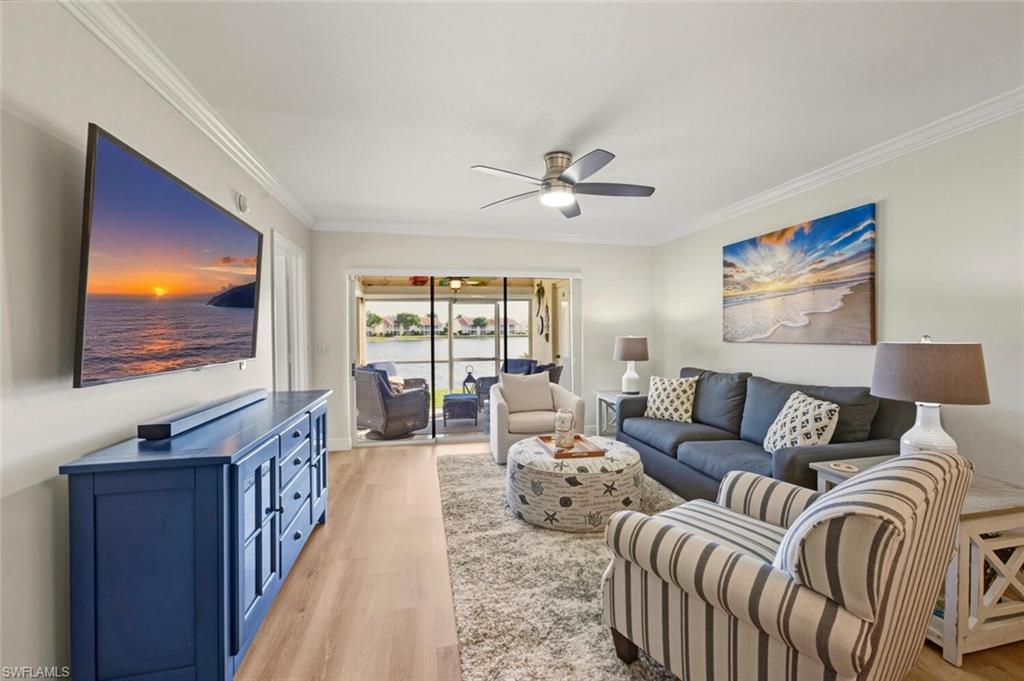 7772 Emerald Circle, Unit 101 Naples, FL 34109 - Photo 10 of 37 a living room with furniture a flat screen tv and a floor to ceiling window