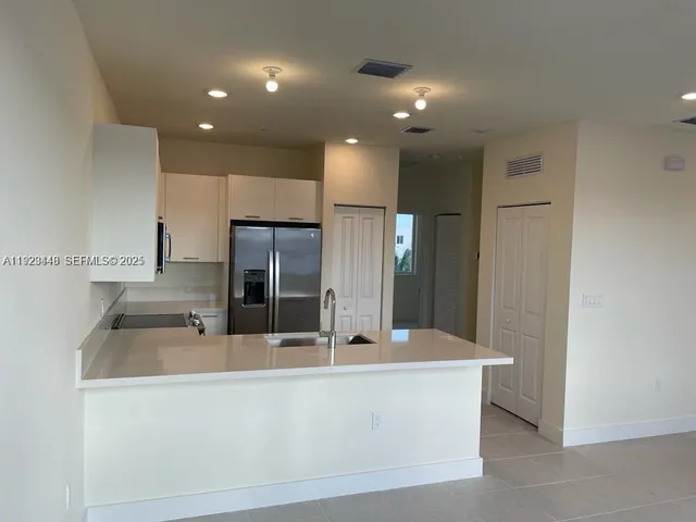 a large kitchen with kitchen island a sink stainless steel appliances and cabinets