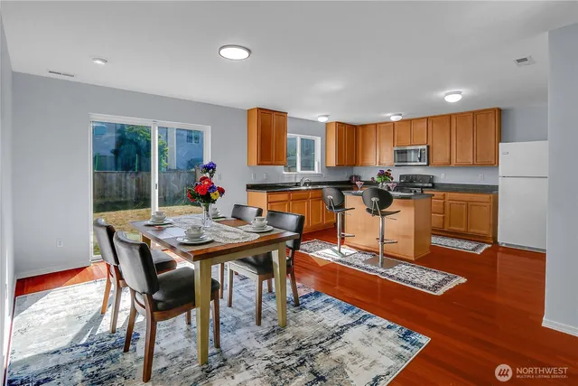 a kitchen with stainless steel appliances granite countertop a stove top oven dining table and chairs
