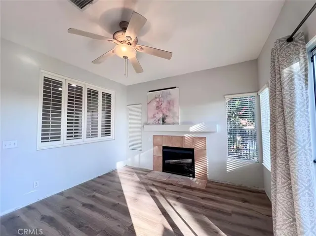 a view of an empty room with wooden floor fireplace and a window