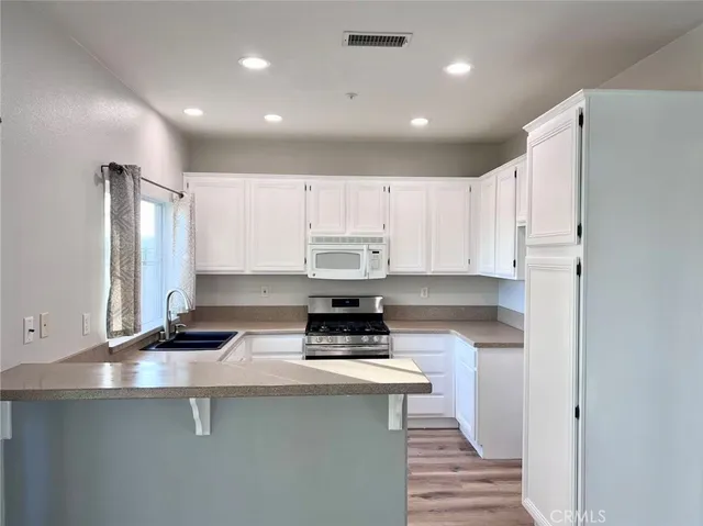 a kitchen with stainless steel appliances a stove a sink a refrigerator and cabinets