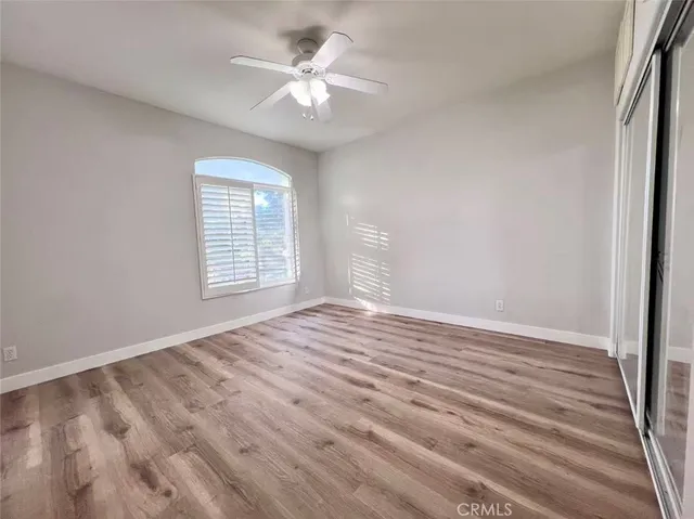 a view of empty room with wooden floor and fan