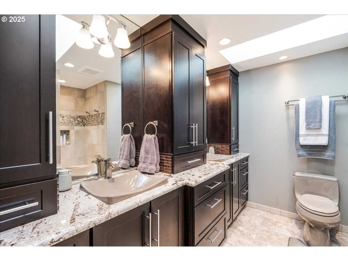 15735 Southwest 88th Avenue Portland, OR 97224 - Photo 19 of 38 a bathroom with a granite countertop sink a toilet and a large mirror