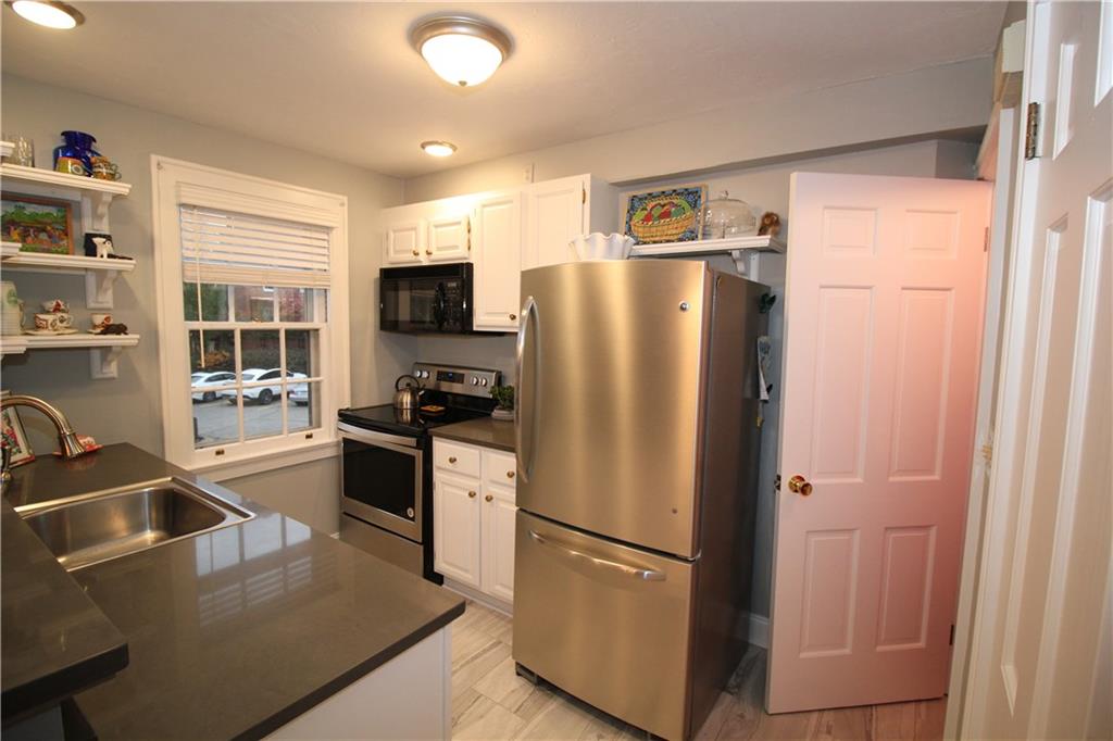 524 Bigham Road Pittsburgh, PA 15211 - Photo 8 of 21 The kitchen as seen from the dining area with classic features such as the aged brass cabinet pulls and the open corniced shelving with touches of modern like the stainless appliances and gray counters.