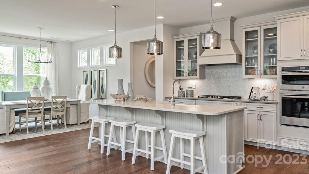 13224 Chopin Ridge Road Huntersville, NC 28078 - Photo 10 of 33 a kitchen with stainless steel appliances granite countertop a stove top oven a sink a dining table and chairs with wooden floor