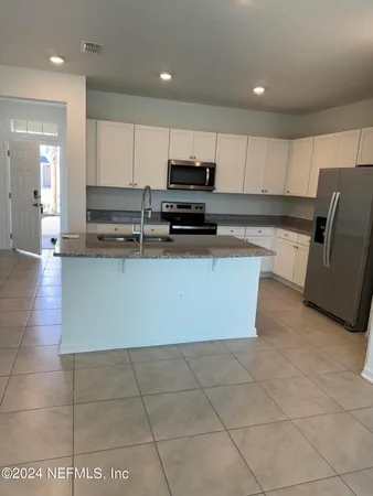 a large kitchen with stainless steel appliances a stove a sink a microwave and a refrigerator