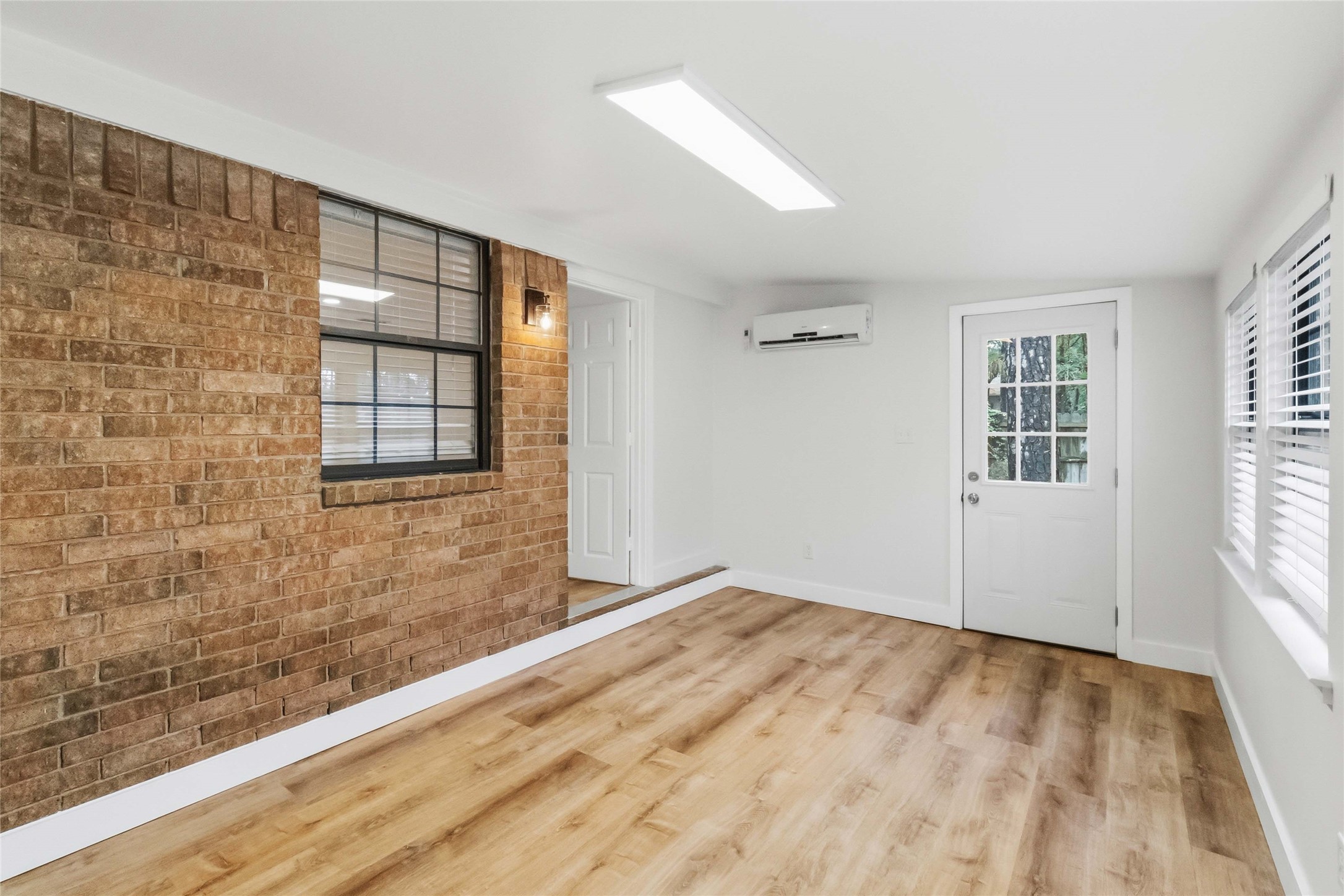 326 Pine View Loop Bastrop, TX 78602 - Photo 23 of 30 A well-lit, adaptable room features warm hardwood flooring and exposed brick accents.