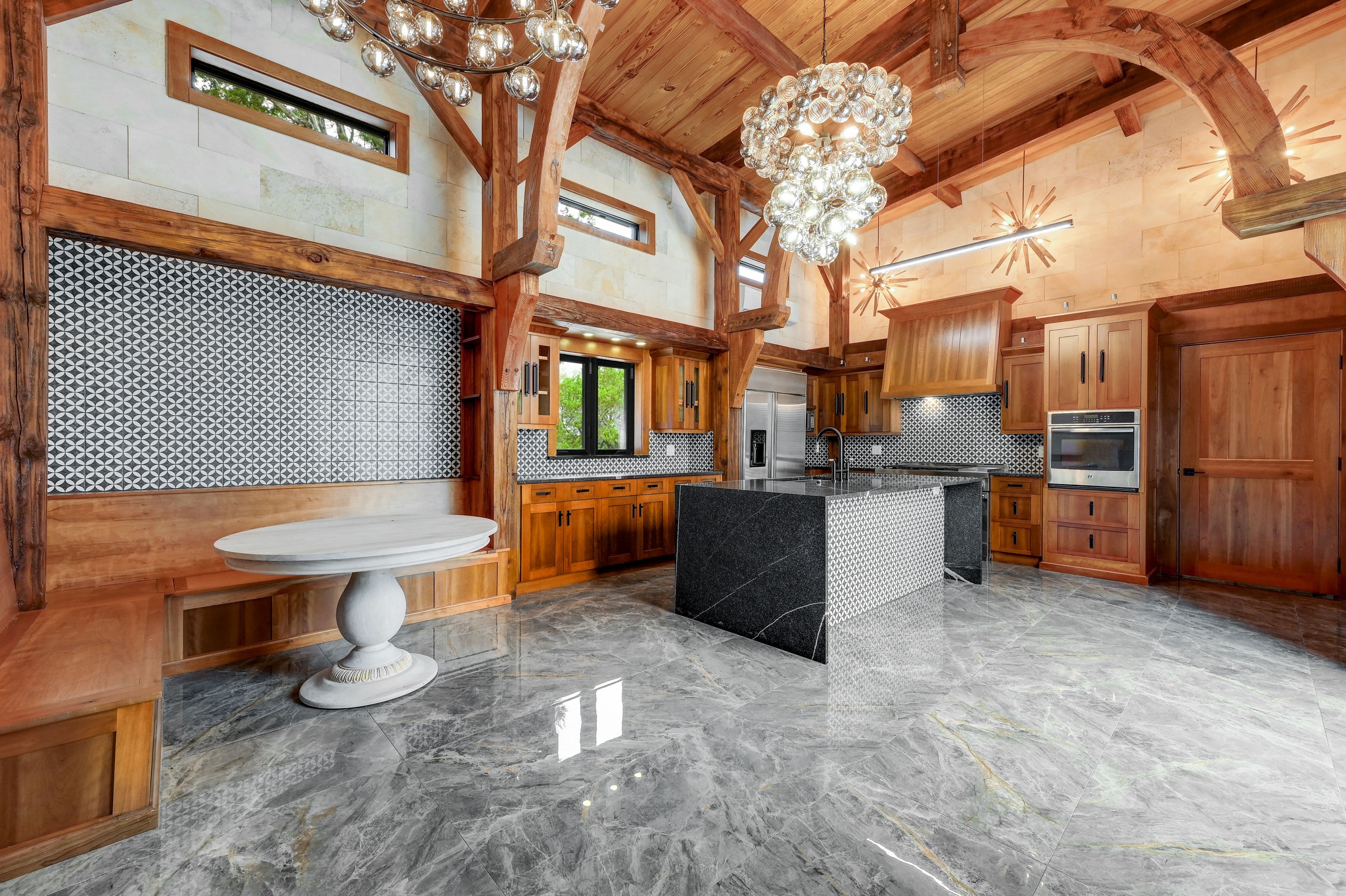 700 Rancho Grande Drive Wimberley, TX 78676 - Photo 9 of 39 Kitchen featuring custom cabinetry, dark stone counters, custom woodwork cathedral ceiling, and travertine walls