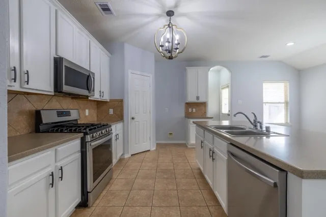 a kitchen with stainless steel appliances granite countertop a sink a stove oven and white cabinets