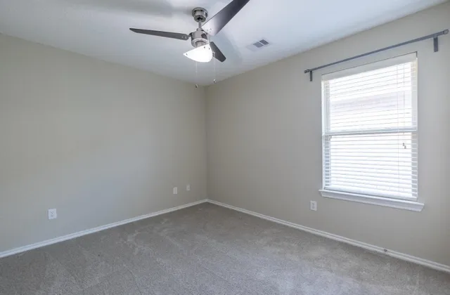 an empty room with a window and a fan