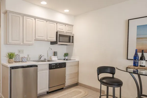 a kitchen with stainless steel appliances a sink a stove a microwave a dining table and chairs