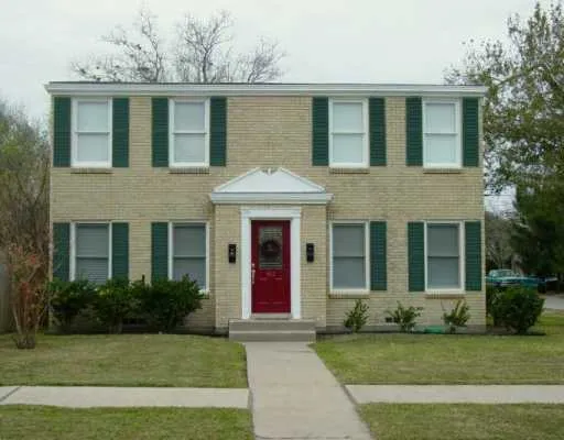 a view of a white house with a large windows and a yard with plants
