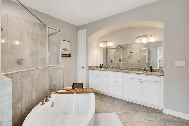 a spacious bathroom with a granite countertop sink a mirror and a bathtub