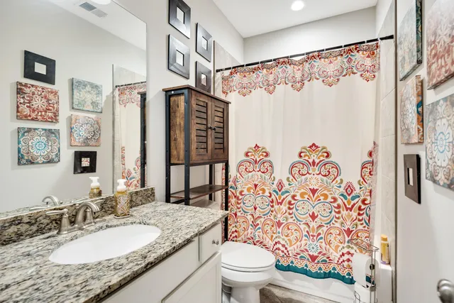 a bathroom with a granite countertop sink toilet and shower
