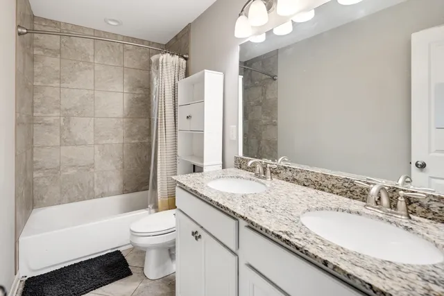 a bathroom with a granite countertop sink toilet mirror and bathtub