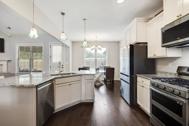 a kitchen with stainless steel appliances a kitchen island hardwood floor sink stove and wooden cabinets