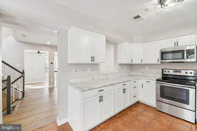 a kitchen with stainless steel appliances granite countertop a stove top oven a sink and white cabinets