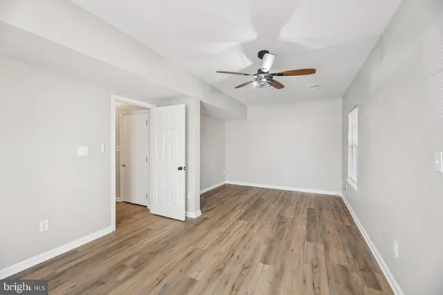 an empty room with wooden floor and ceiling fan