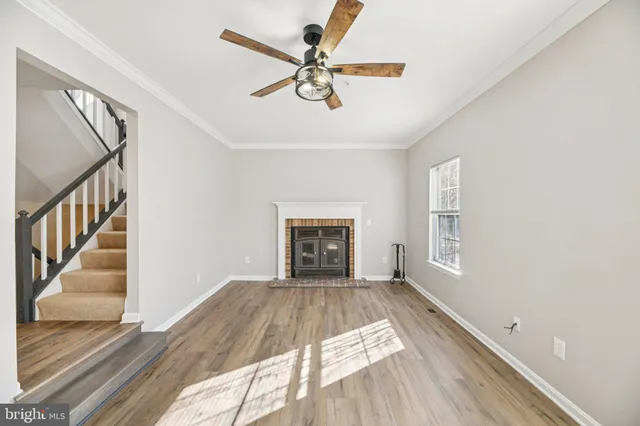 a view of an empty room with wooden floor fireplace and a window