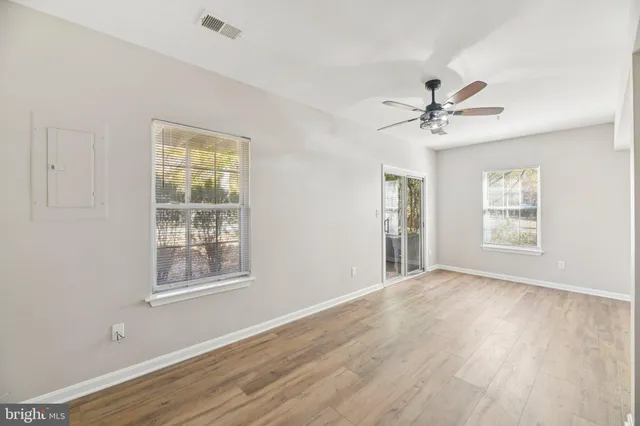 a view of an empty room with a window and wooden floor