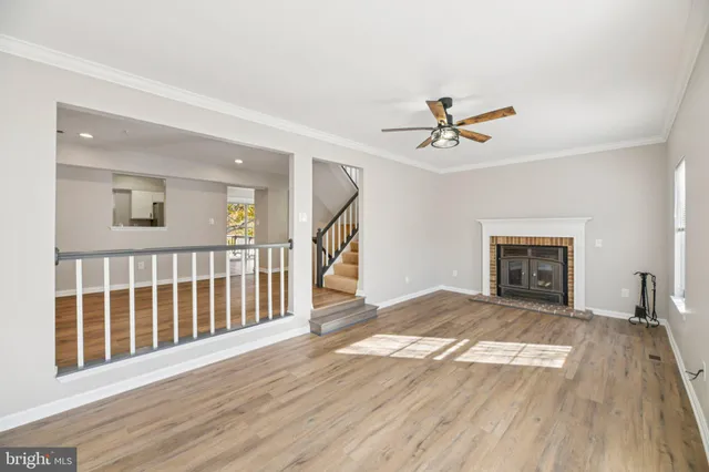 a view of a livingroom with wooden floor a ceiling fan and windows