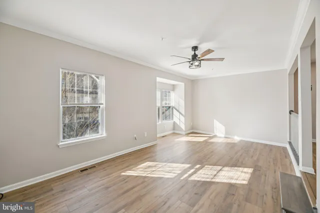 an empty room with wooden floor and ceiling fan
