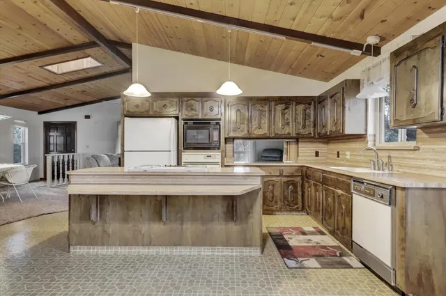 a view of a kitchen with kitchen island a sink stainless steel appliances and cabinets