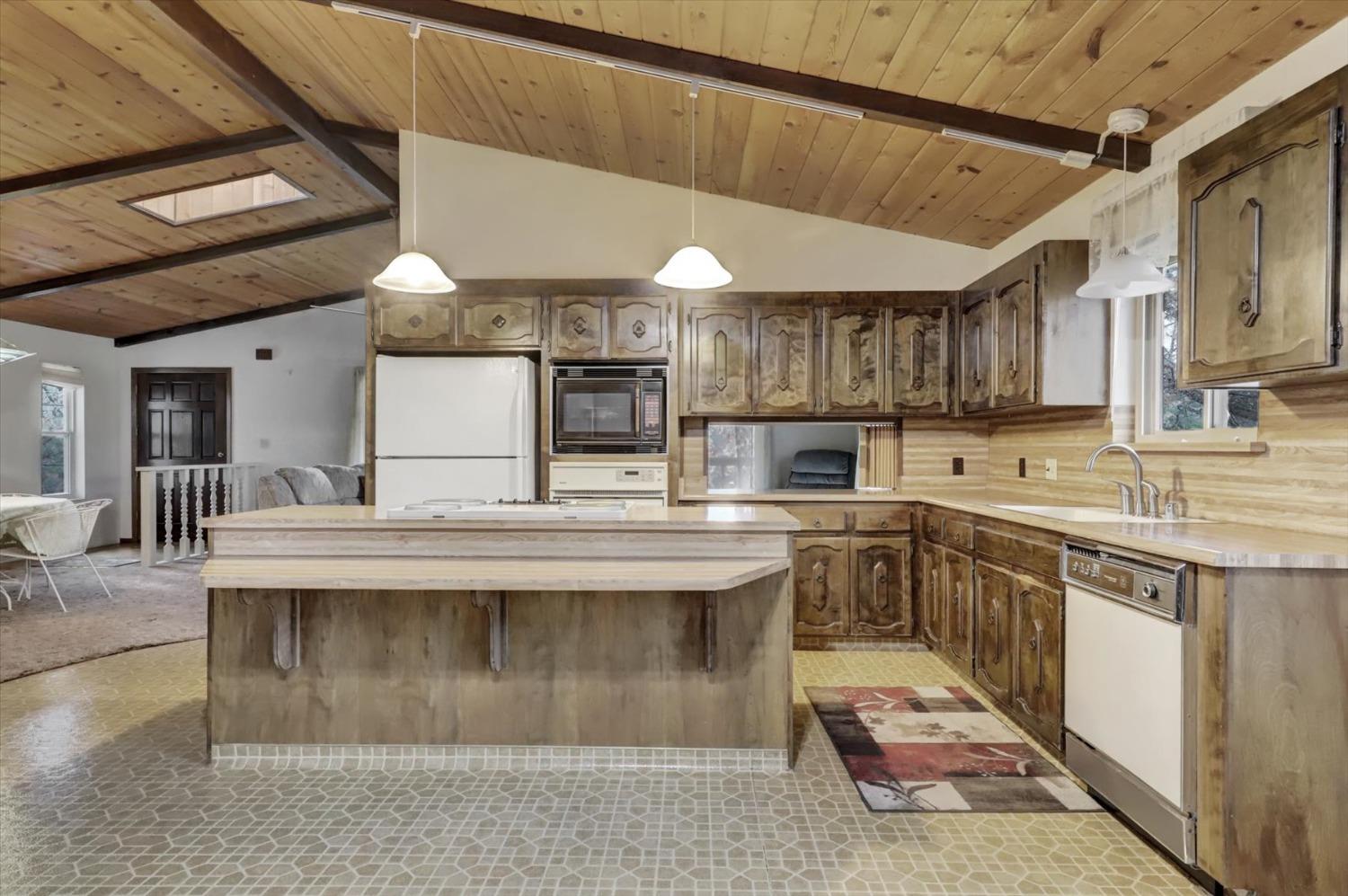 13032 Thistle Loop Penn Valley, CA 95946 - Photo 7 of 30 a view of a kitchen with kitchen island a sink stainless steel appliances and cabinets