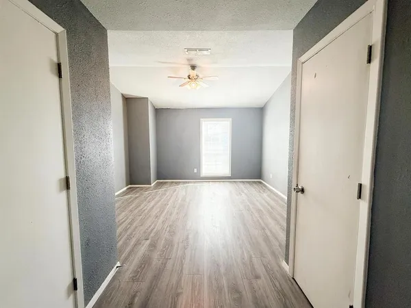 a view of an empty room with wooden floor and a window
