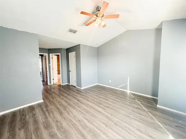 a view of an empty room with window and a chandelier fan