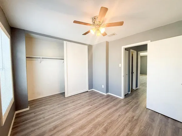 a view of a room with wooden floor and a ceiling fan
